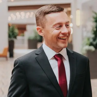 Smiling man in a black suit and red tie