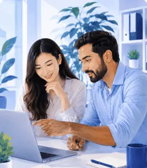 Two coworkers reviewing a laptop in a bright office